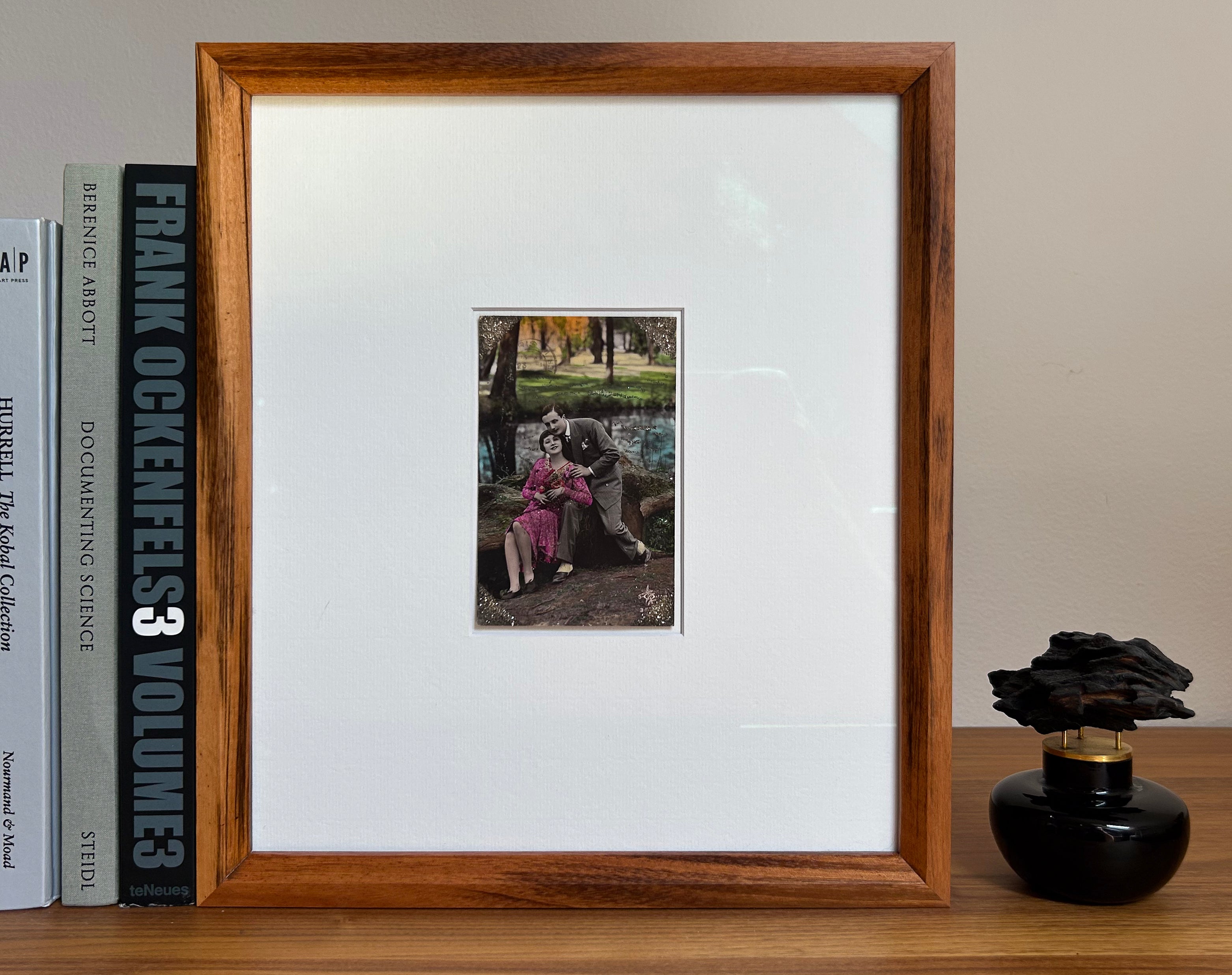 Starts with a great story - Framed 1920s Hand-Tinted and glittered Postcard featuring a tender couple’s embrace in a park – Vintage Romantic Art in Tigerwood Frame
