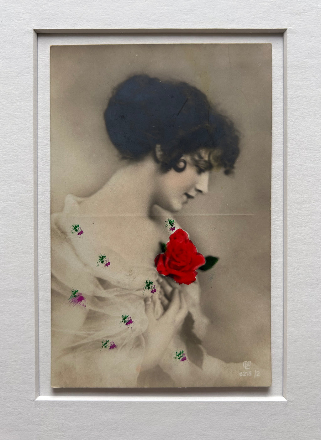 By any other name - Framed 1920s Hand-Colored Postcard featuring a soft portrait of a woman holding a flower – Vintage Parisian Portrait in Merbau wood Frame
