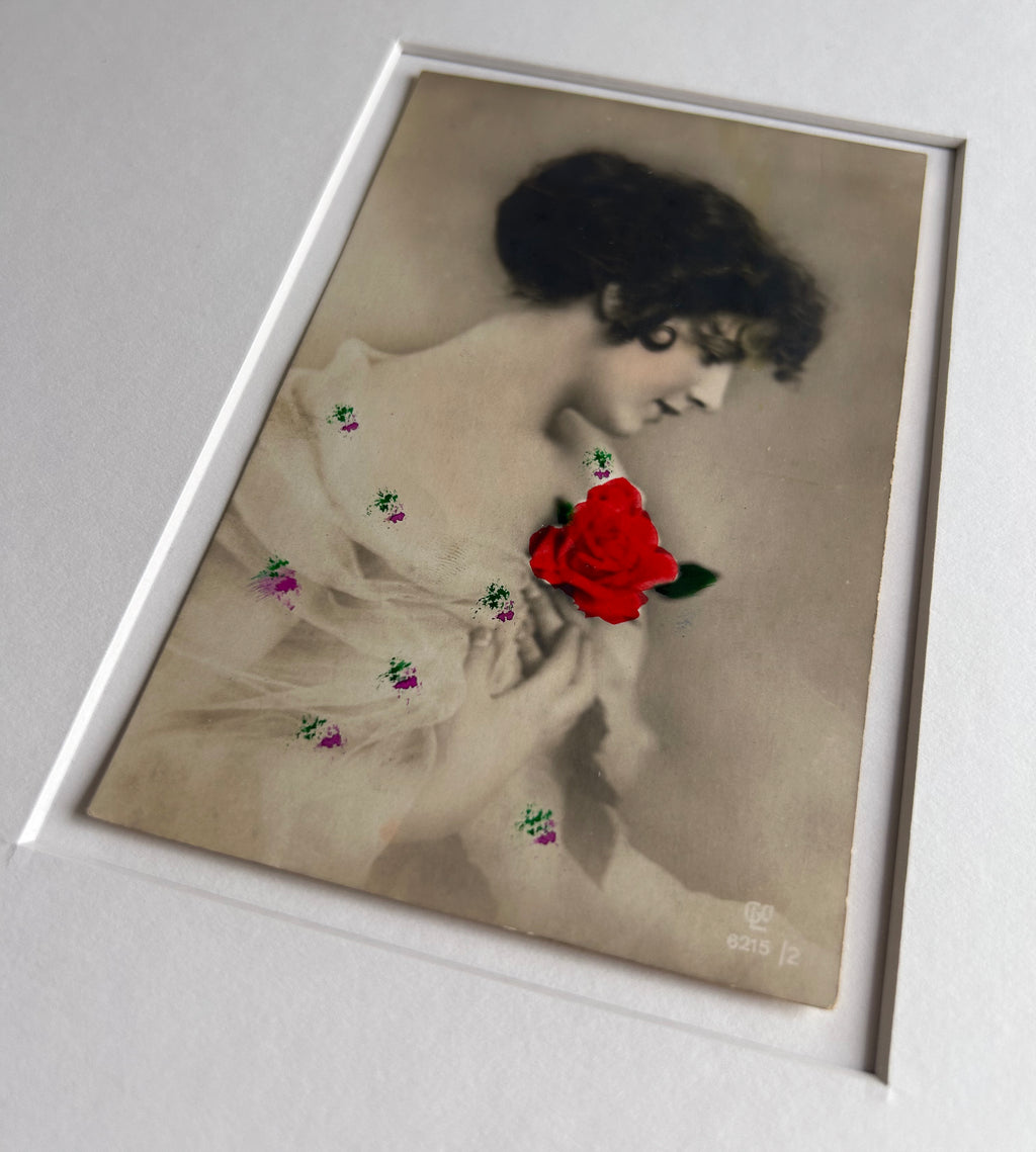 By any other name - Framed 1920s Hand-Colored Postcard featuring a soft portrait of a woman holding a flower – Vintage Parisian Portrait in Merbau wood Frame
