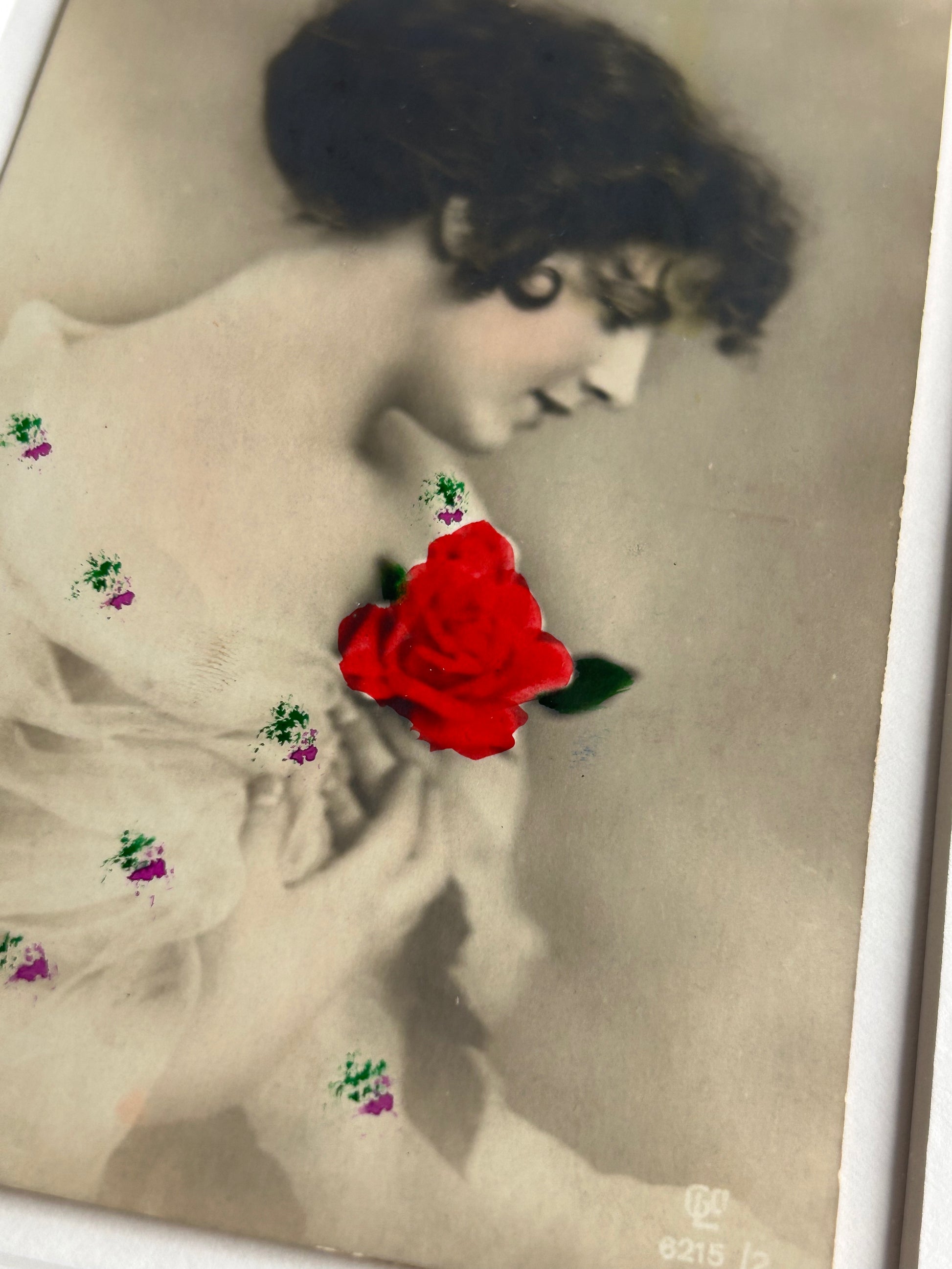 By any other name - Framed 1920s Hand-Colored Postcard featuring a soft portrait of a woman holding a flower – Vintage Parisian Portrait in Merbau wood Frame