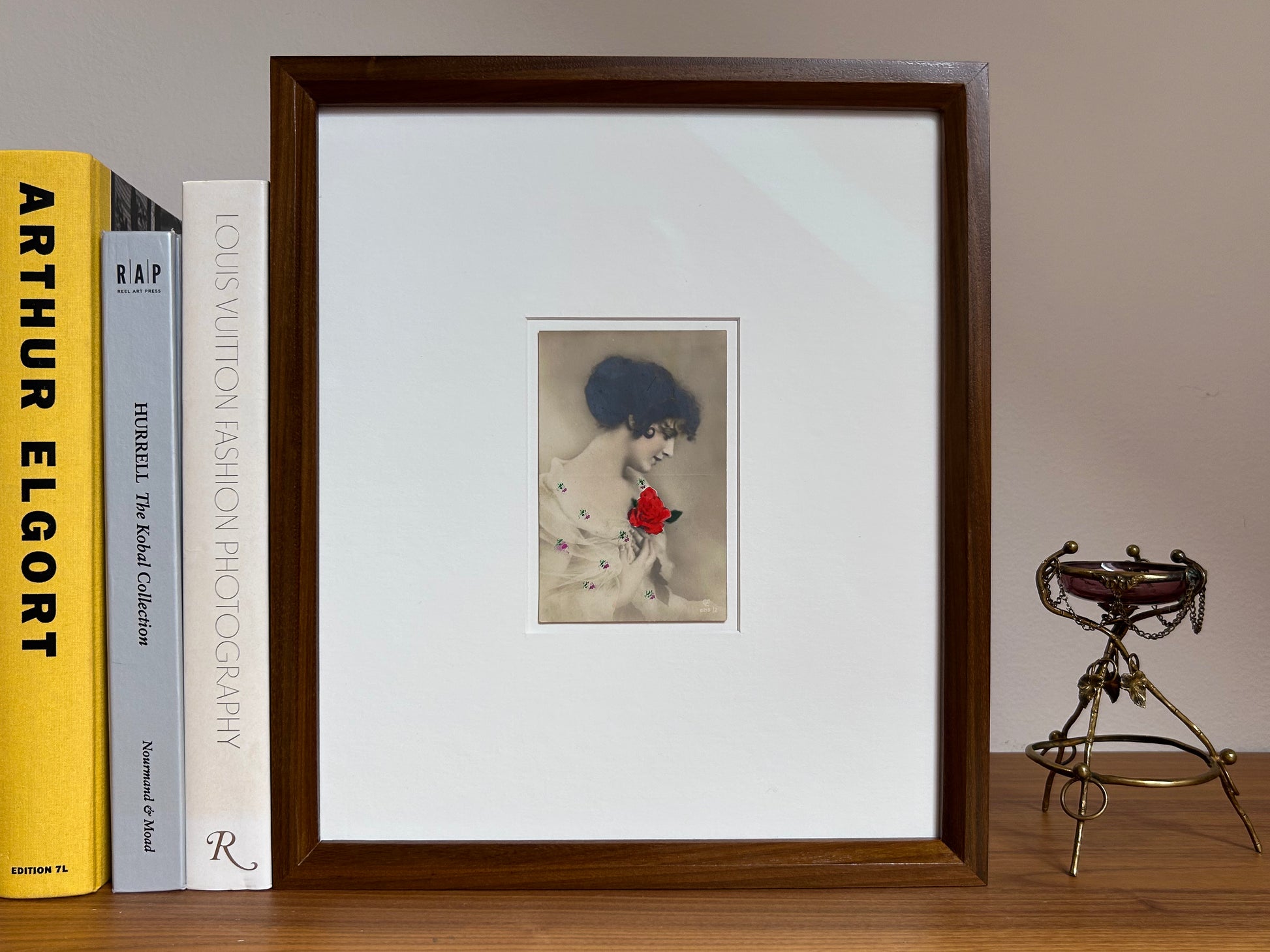 By any other name - Framed 1920s Hand-Colored Postcard featuring a soft portrait of a woman holding a flower – Vintage Parisian Portrait in Merbau wood Frame