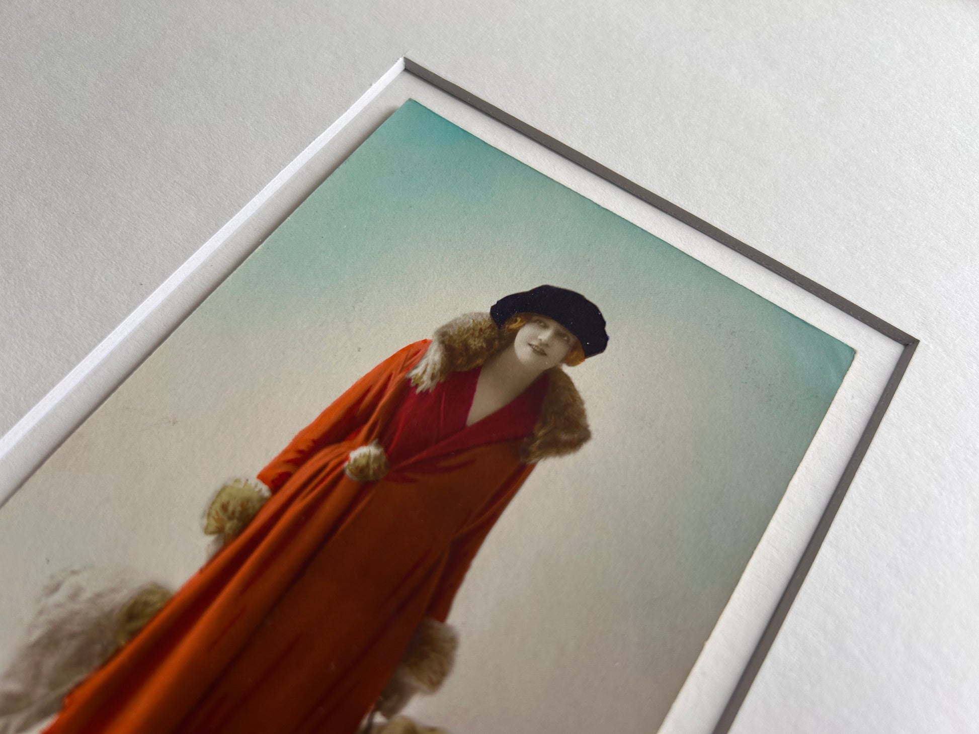 Framed 1920s Fashion Postcard with a poised female model in a fur-trimmed orange coat and black beret, standing confidently beside a Borzoi dog in a handmade Jatoba Wood Frame