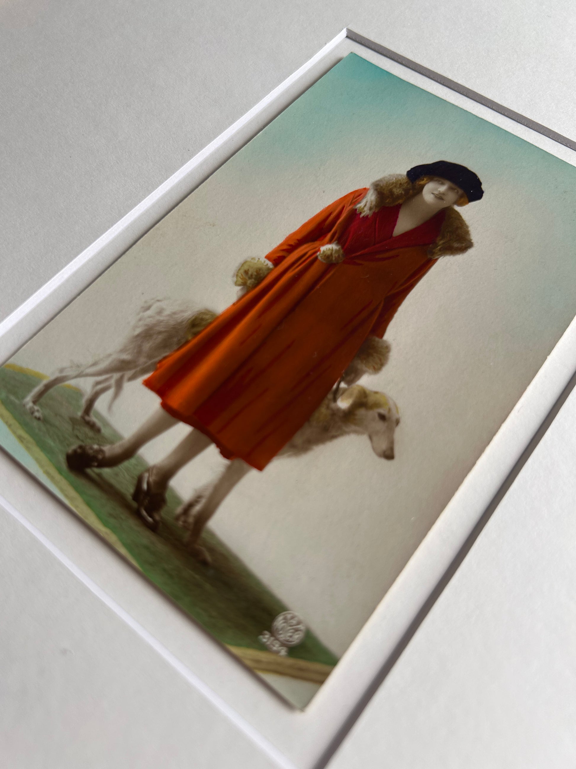 Framed 1920s Fashion Postcard with a poised female model in a fur-trimmed orange coat and black beret, standing confidently beside a Borzoi dog in a handmade Jatoba Wood Frame