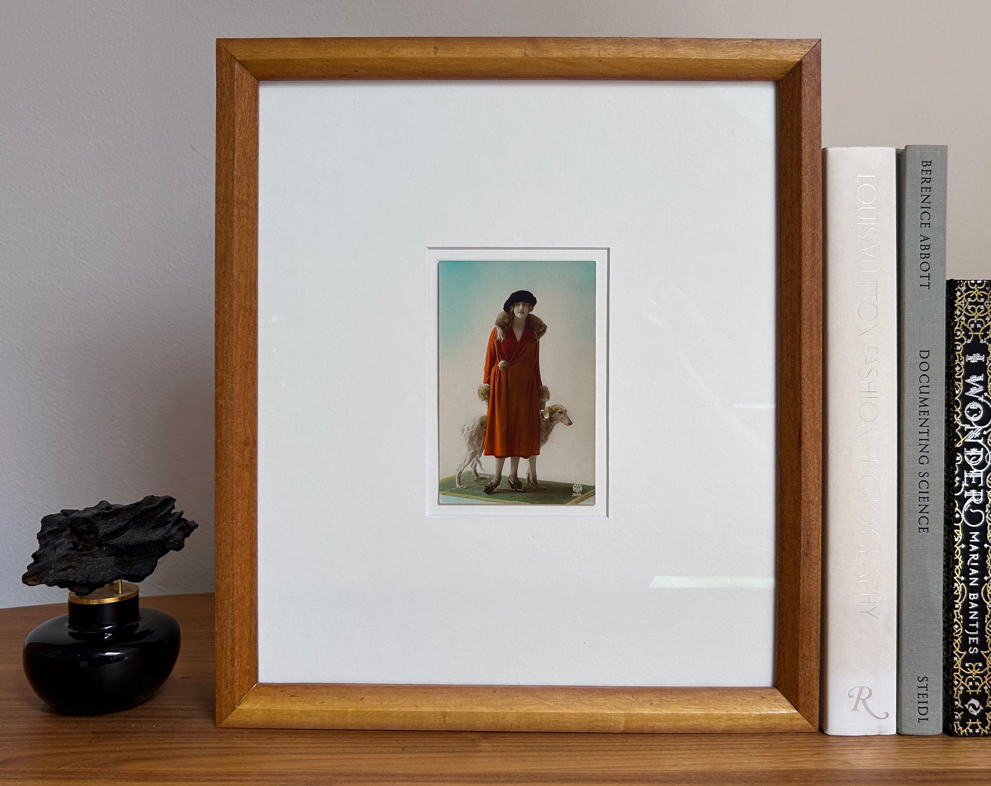Framed 1920s Fashion Postcard with a poised female model in a fur-trimmed orange coat and black beret, standing confidently beside a Borzoi dog in a handmade Jatoba Wood Frame