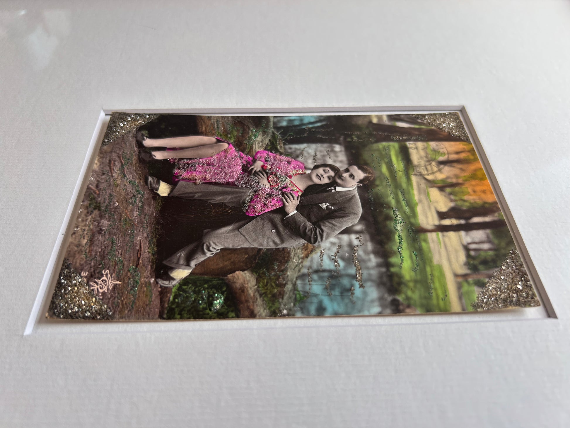 Starts with a great story - Framed 1920s Hand-Tinted and glittered Postcard featuring a tender couple’s embrace in a park – Vintage Romantic Art in Tigerwood Frame